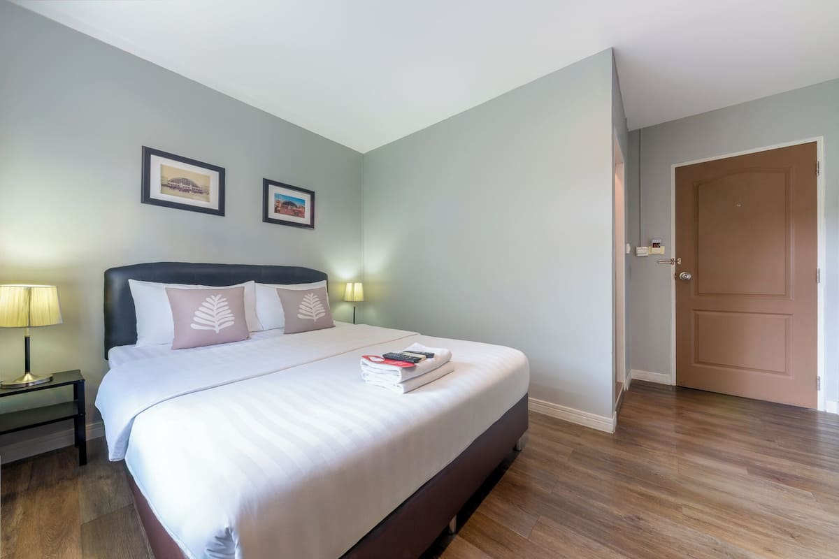 Cama bem arrumada com almofadas, abajur e quadro na parede.