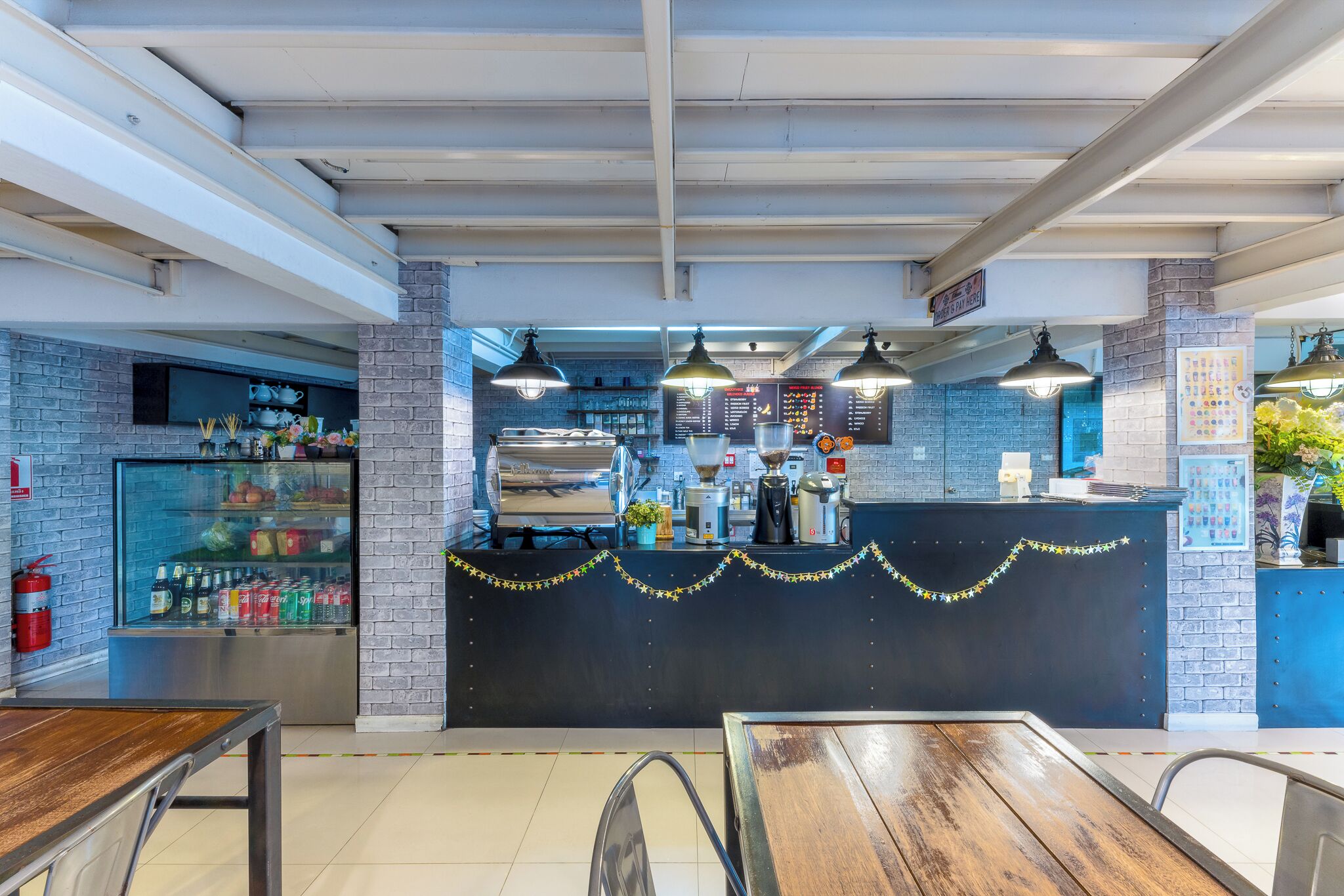 Interior de un restaurante con paredes de ladrillo, una barra con una carta y una vitrina refrigerada.