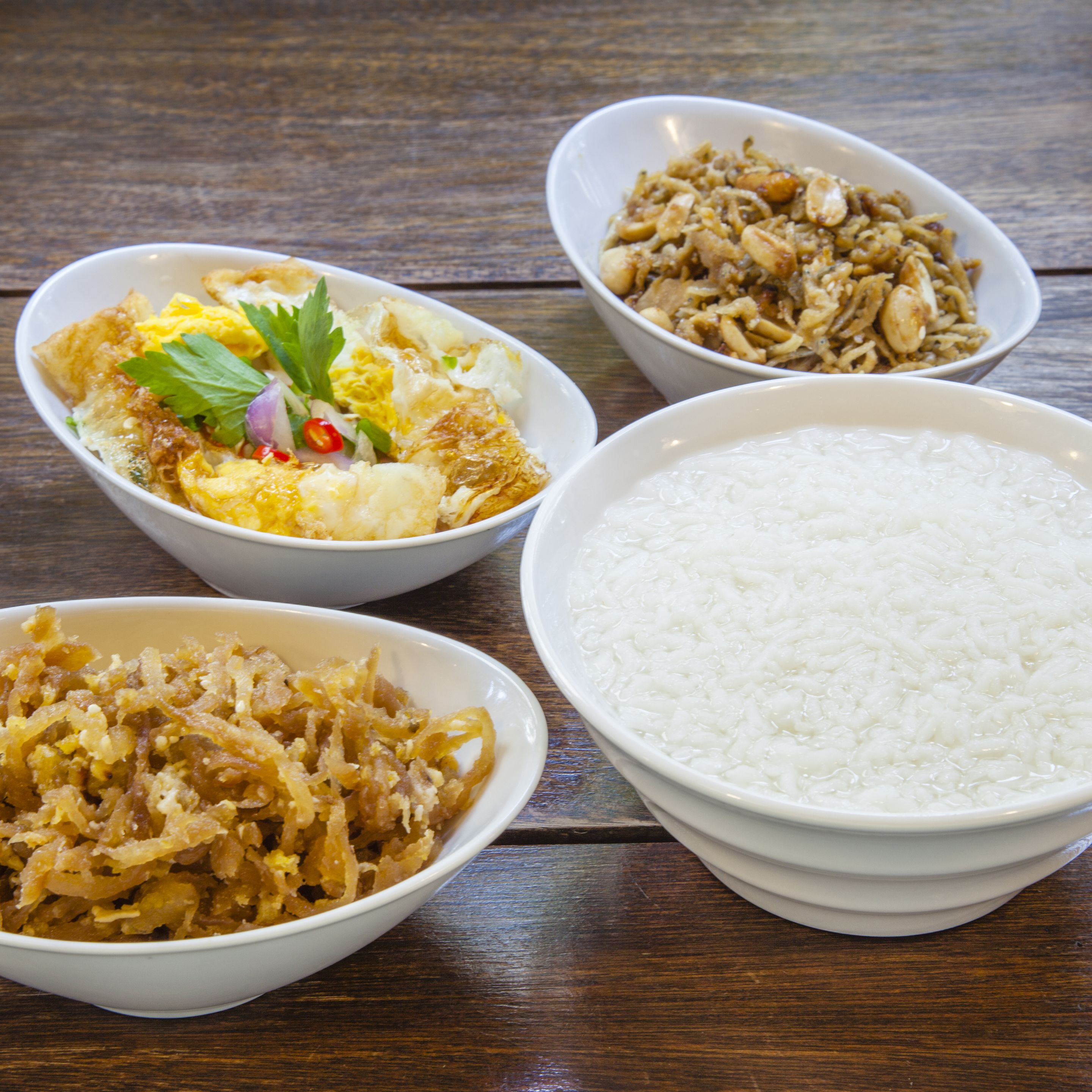 A table with four bowls of food and a bowl of rice.