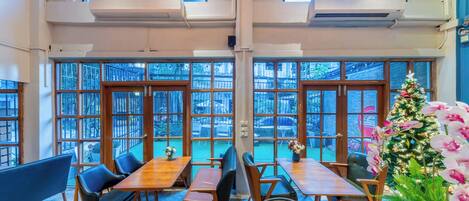A restaurant with large windows, wooden tables, and chairs.