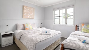 Un dormitorio limpio y moderno con una cama grande, mesitas de noche y una ventana con persianas.