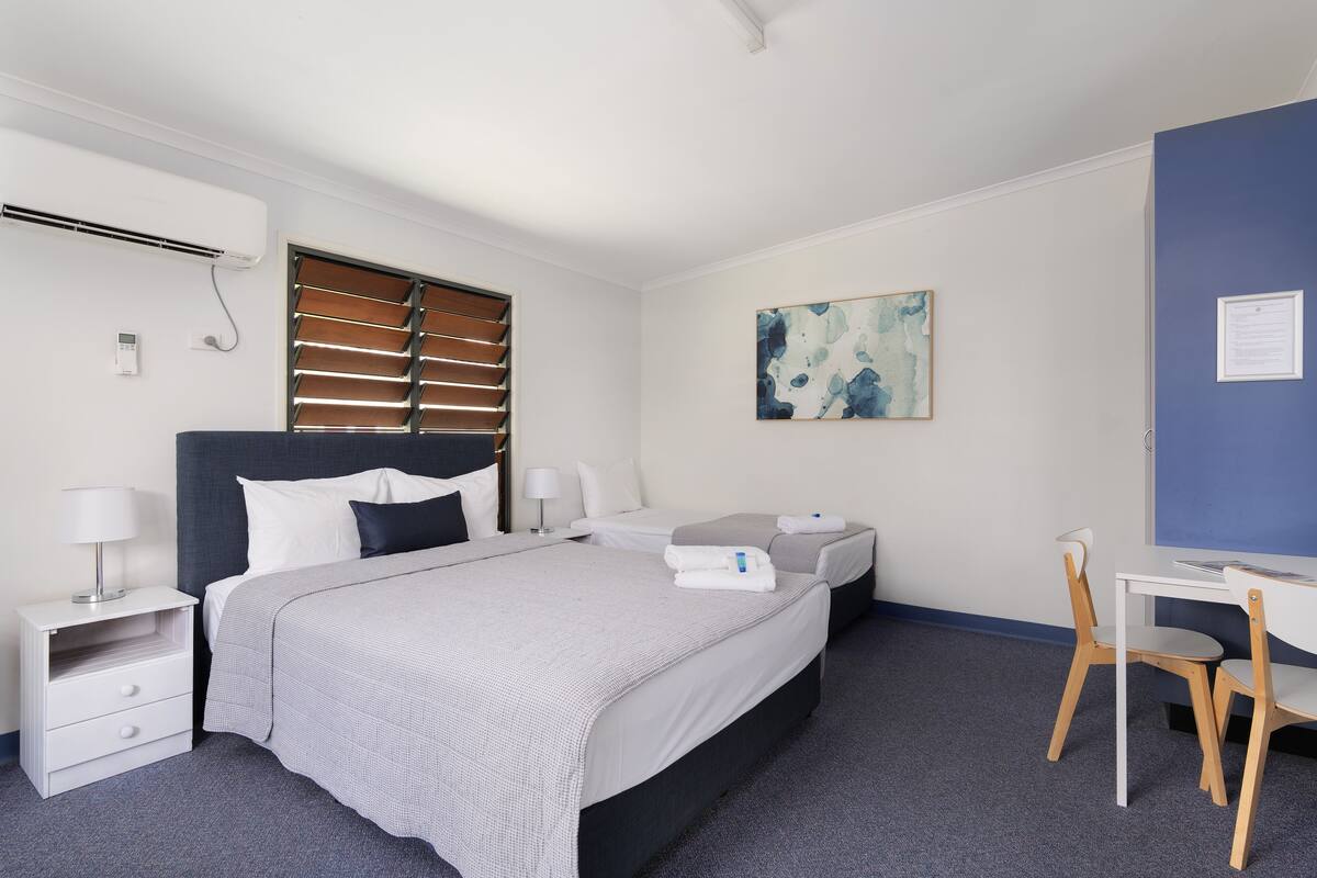 Une chambre d’hôtel avec un grand lit, deux tables de chevet, un bureau et une chaise.