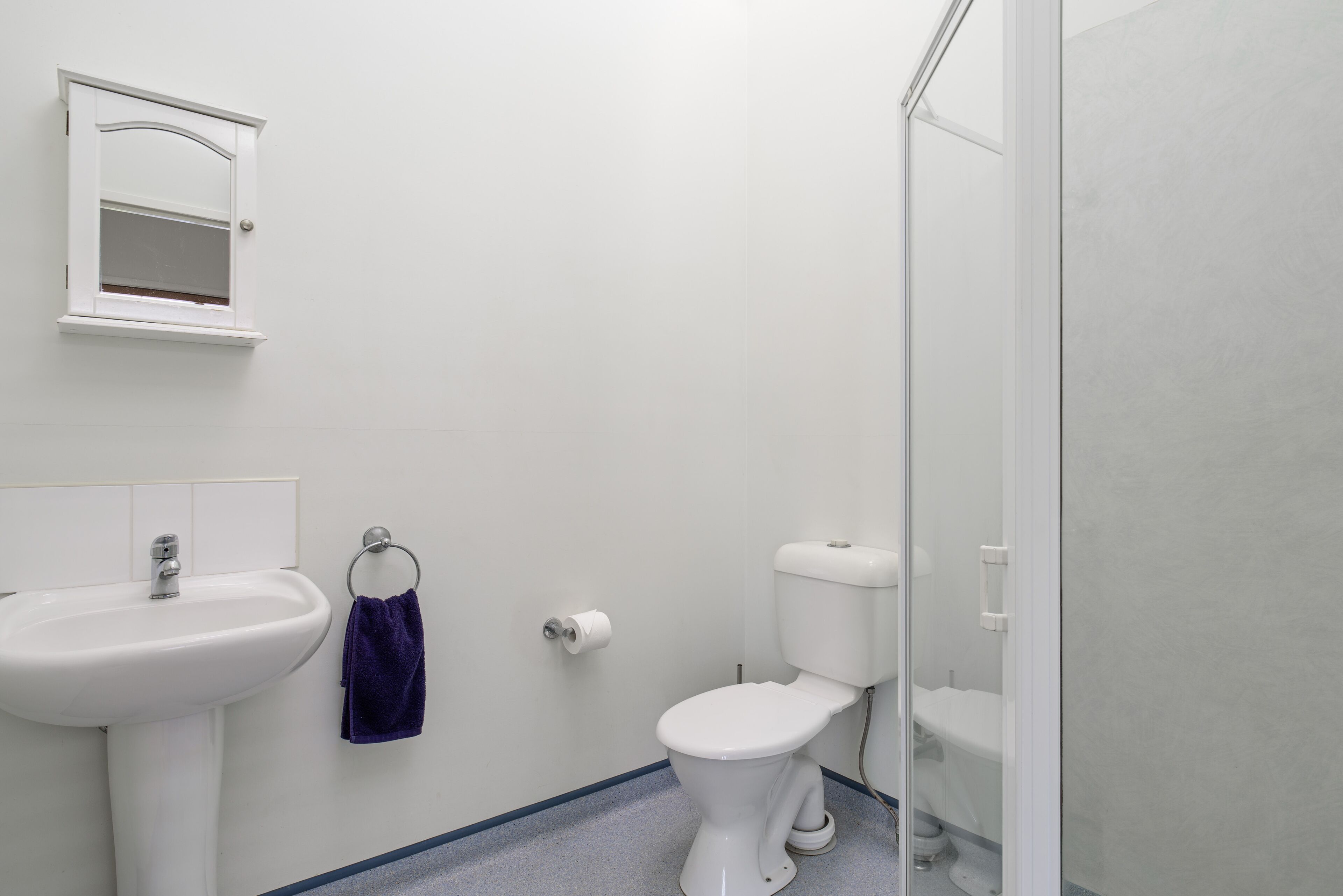 A bathroom with a white sink, toilet, and a small mirror.