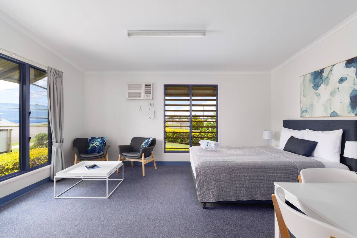 Une chambre d’hôtel équipée d’un lit, d’un bureau, d’une chaise et d’une grande fenêtre donnant sur un beau paysage.