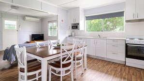 Una cocina moderna con armarios blancos, una mesa de comedor de madera y un amplio ventanal.