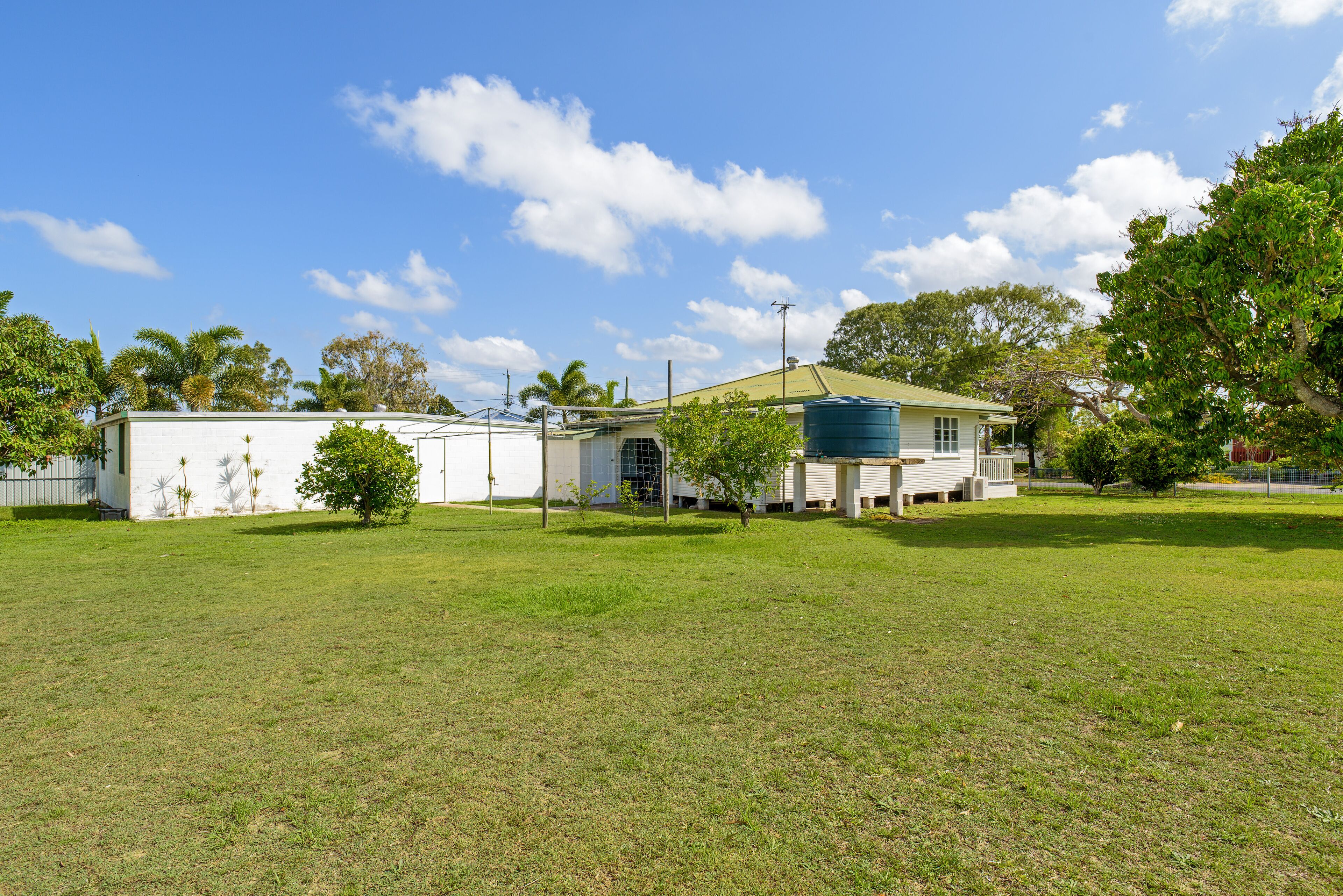 Una propiedad residencial con un amplio césped, una casa con techo verde y un depósito de agua.