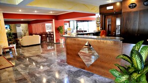 A hotel lobby with a reception desk, seating area, and a dining space. - Santa Marina Hotel Apartments (Kos)