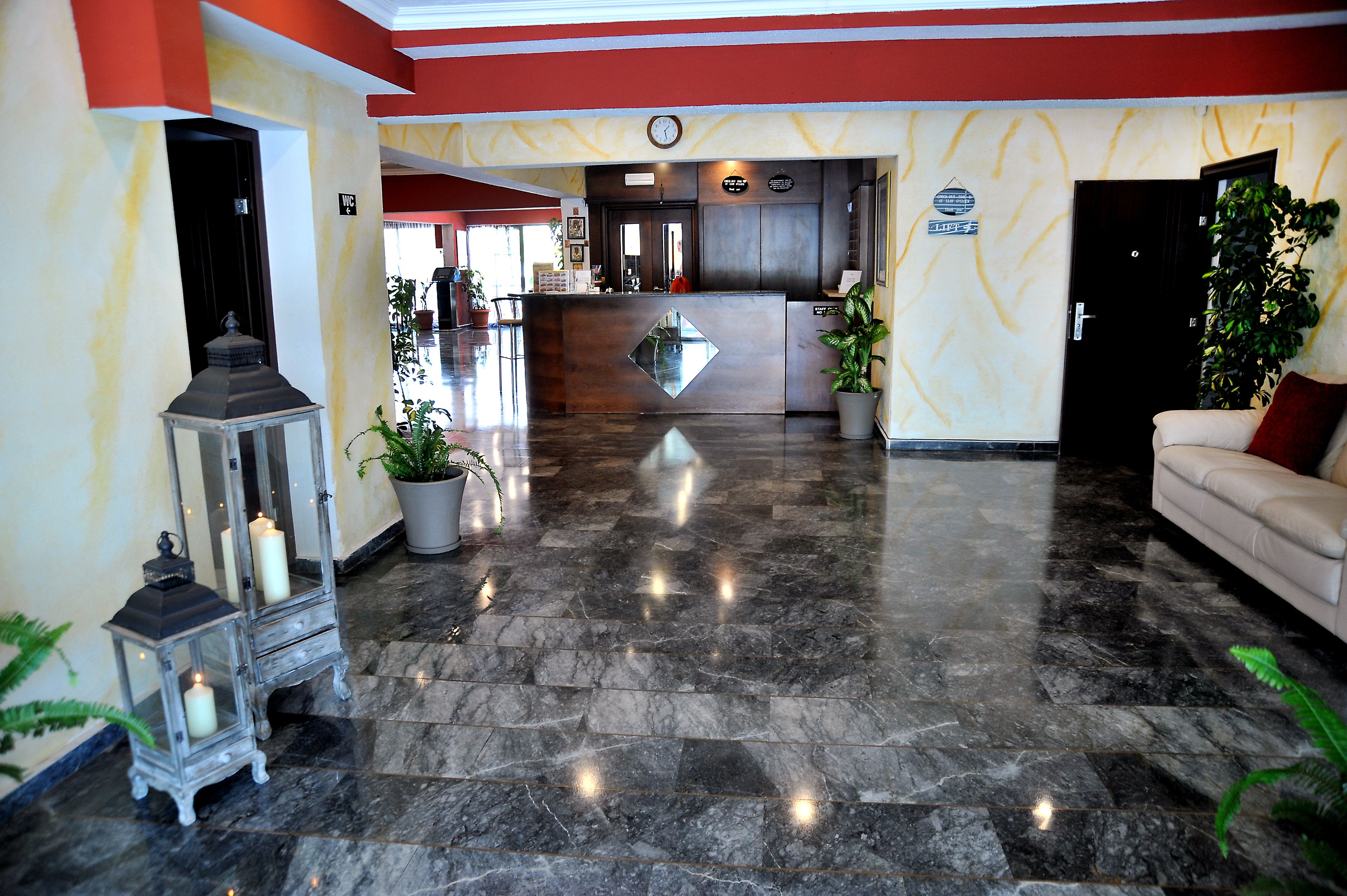 Un vestíbulo de hotel con mostrador de recepción, un sofá y plantas en macetas.
