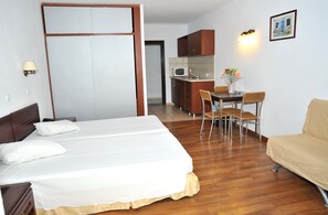 A hotel room with a bed, a dining table with chairs, a kitchenette, and a sofa. - Santa Marina Hotel Apartments (Kos)