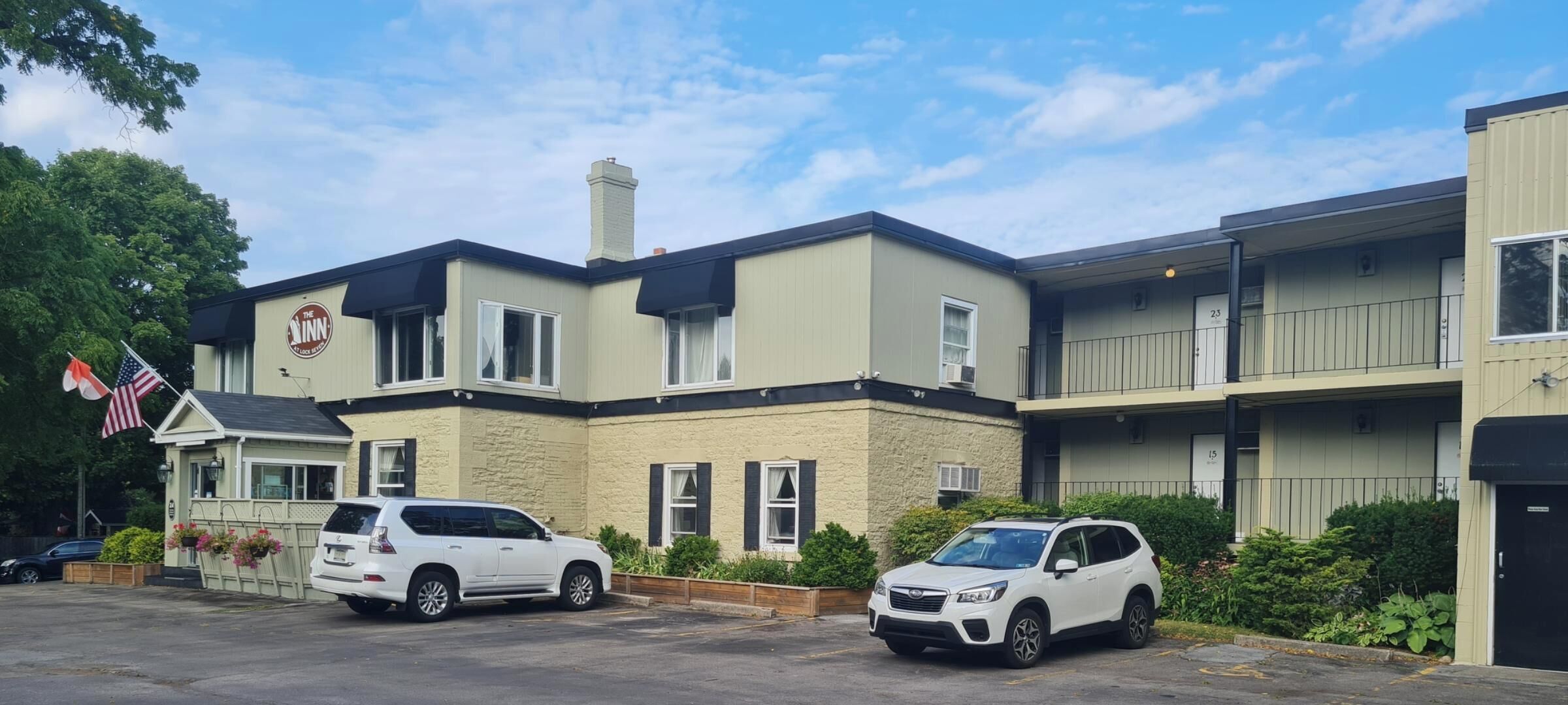 A building with a sign reading "The Inn" and two parked SUVs.