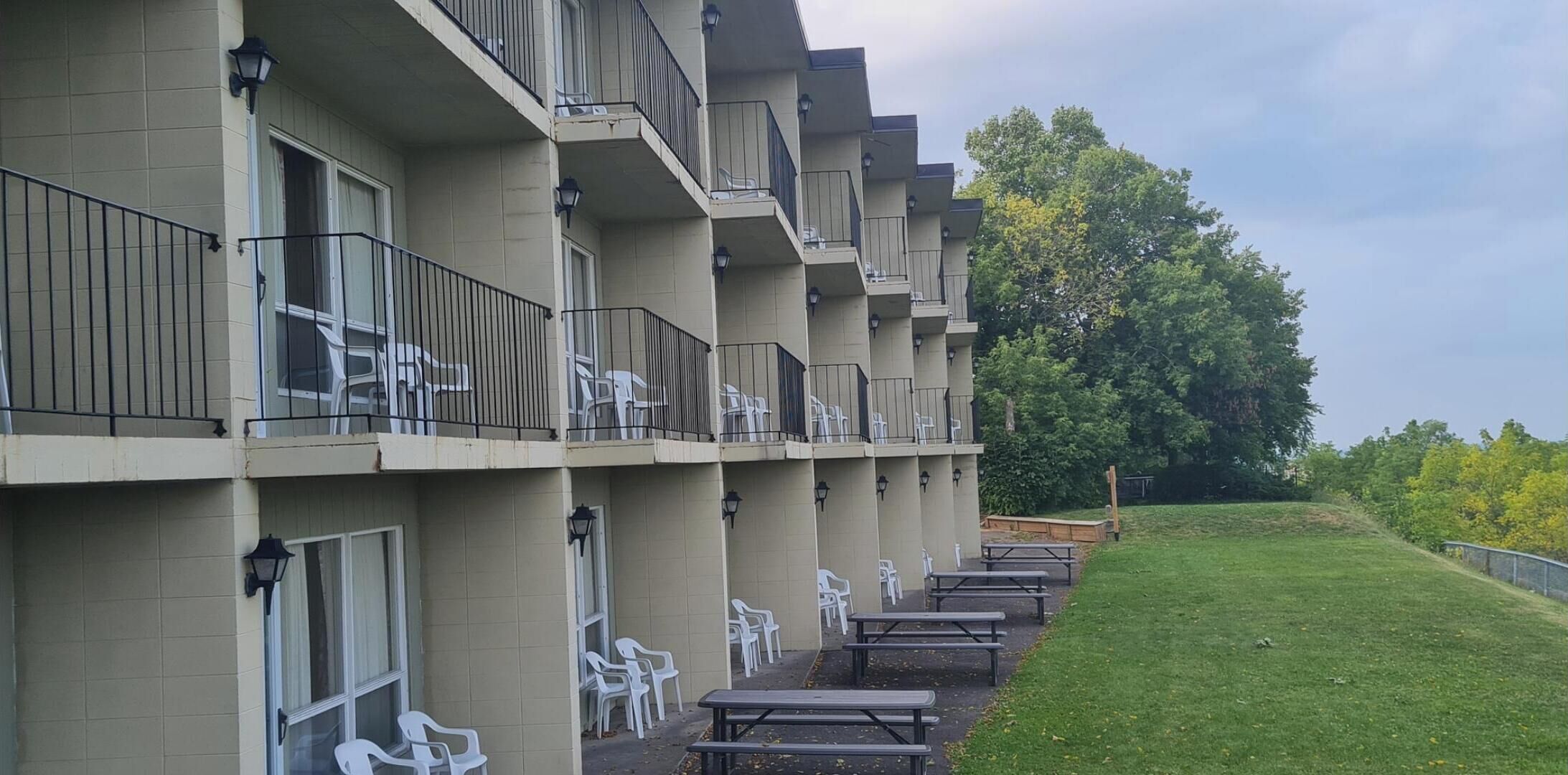 A multi-story hotel with balconies, outdoor seating, and a grassy area.