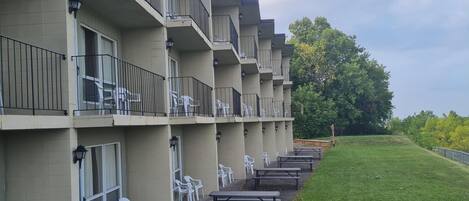 A multi-story hotel with balconies, outdoor seating, and a grassy area.