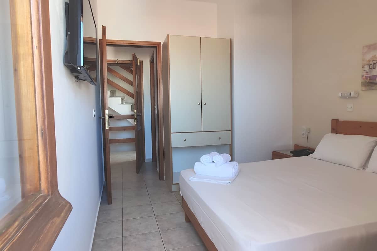A bedroom with a bed, a wardrobe, a desk, and a staircase.