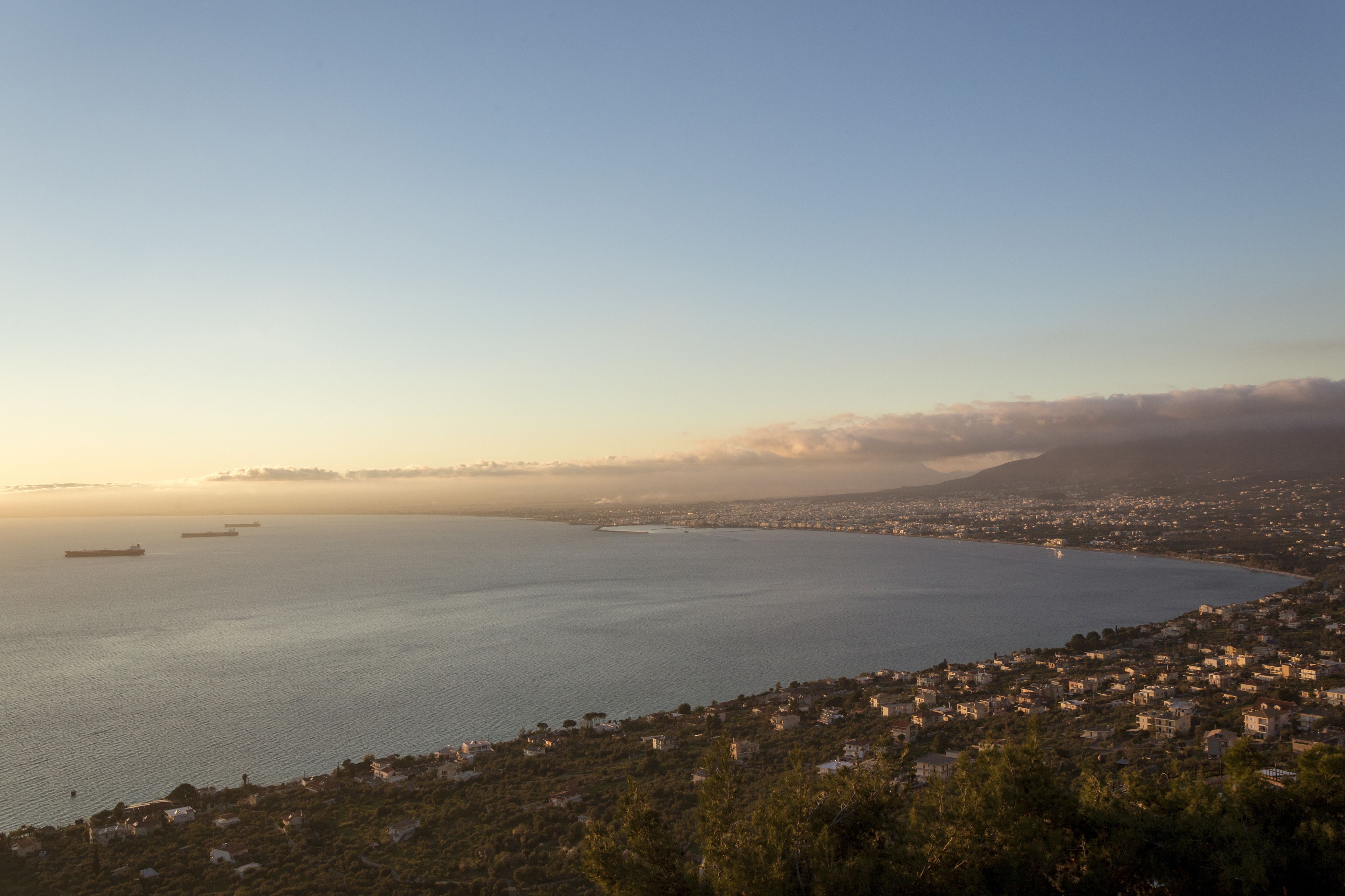 A coastal cityscape with a view of the sea, ships, and residential buildings.