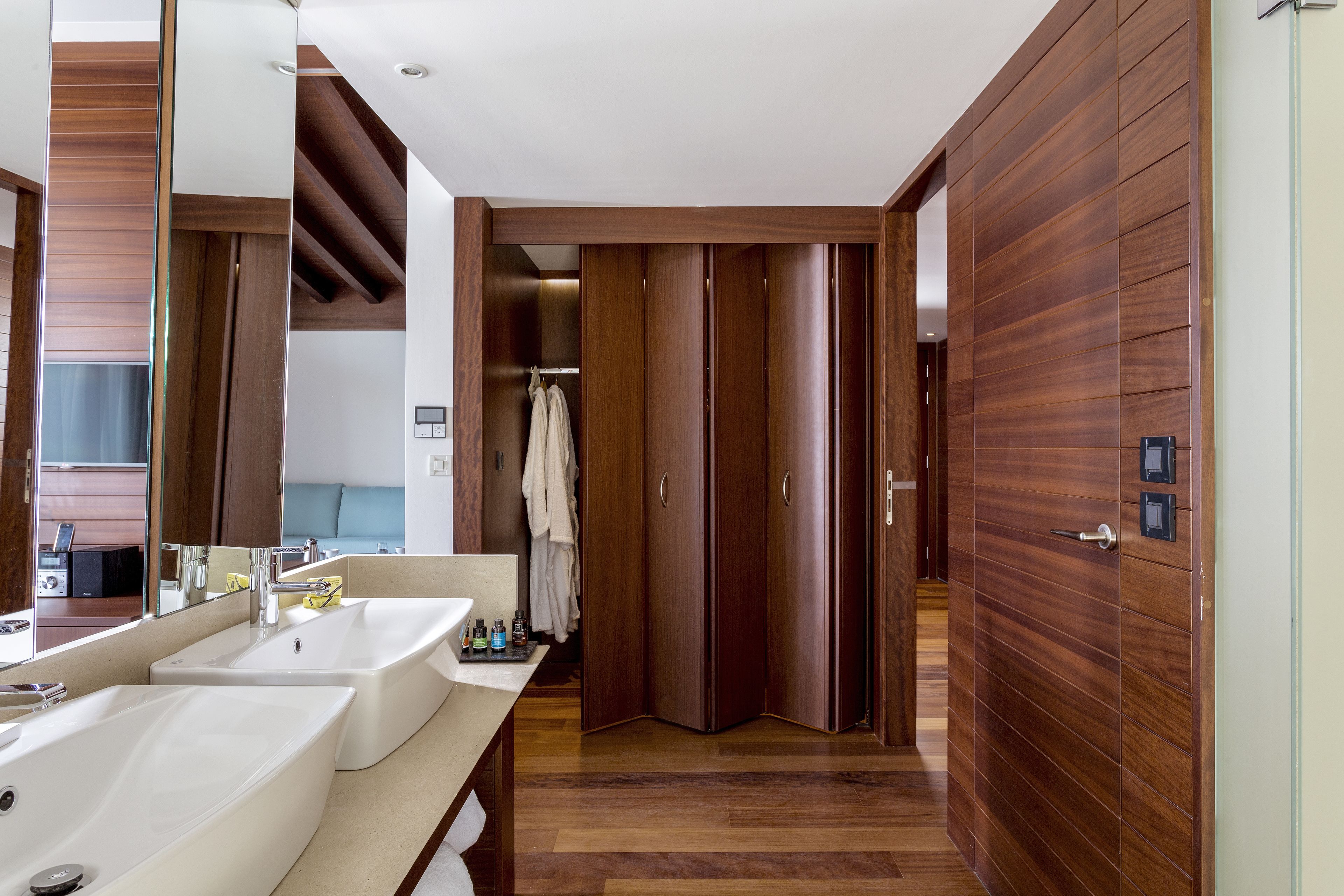 A modern bathroom with two sinks, a mirror, and wooden paneling.