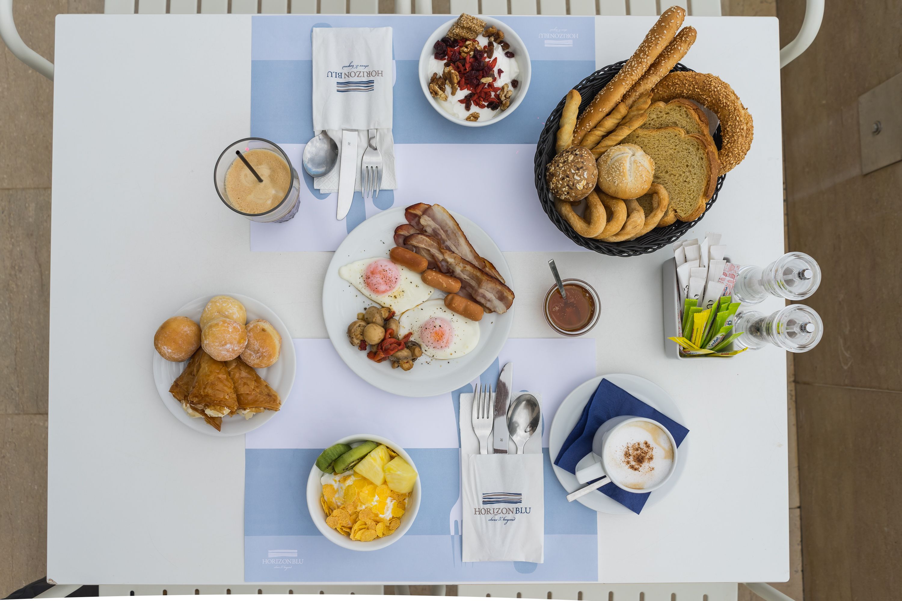 A breakfast buffet with various dishes, including eggs, bacon, pastries, and bread.