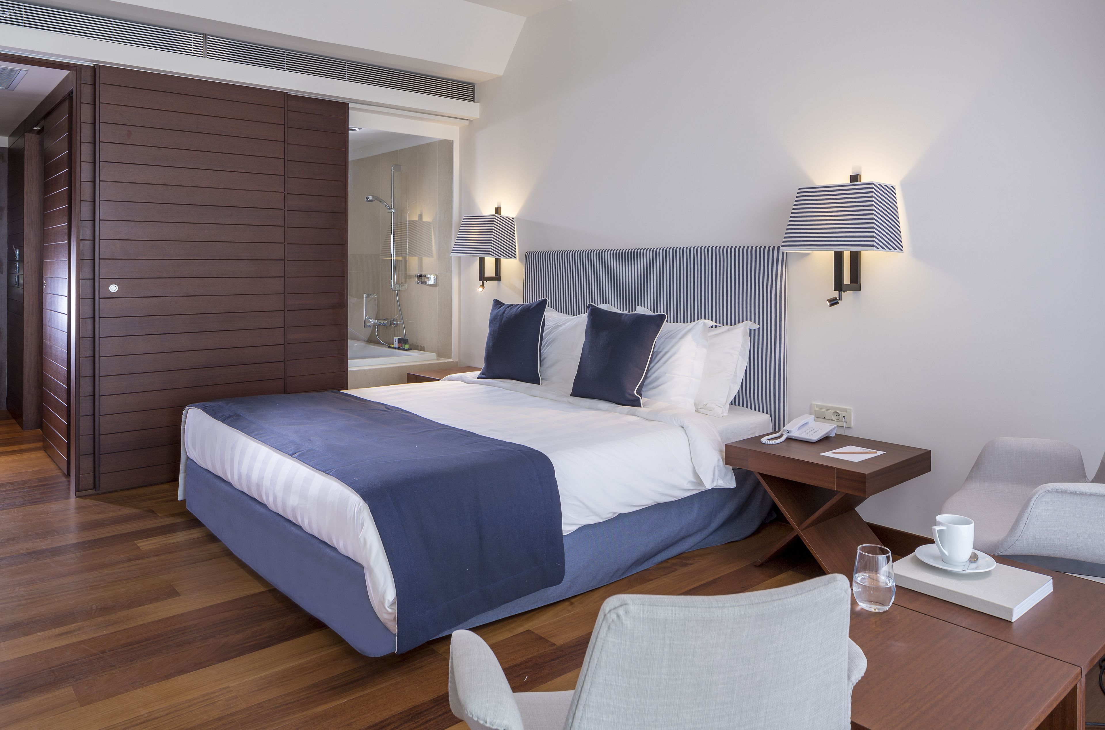 Ein modernes Hotelzimmer mit einem großen Bett, Nachttischen, einem Schreibtisch und einem Sessel.