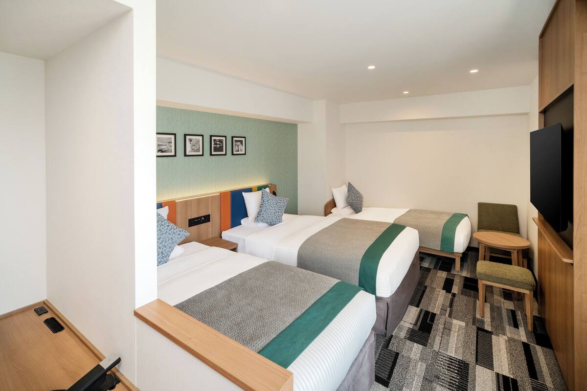 Une chambre d’hôtel avec deux lits, une petite table, une chaise et un téléviseur.