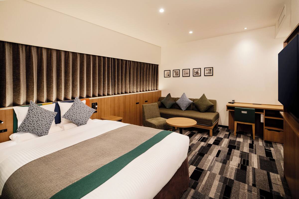 Une chambre d’hôtel avec un grand lit, un canapé, un bureau et une petite table.