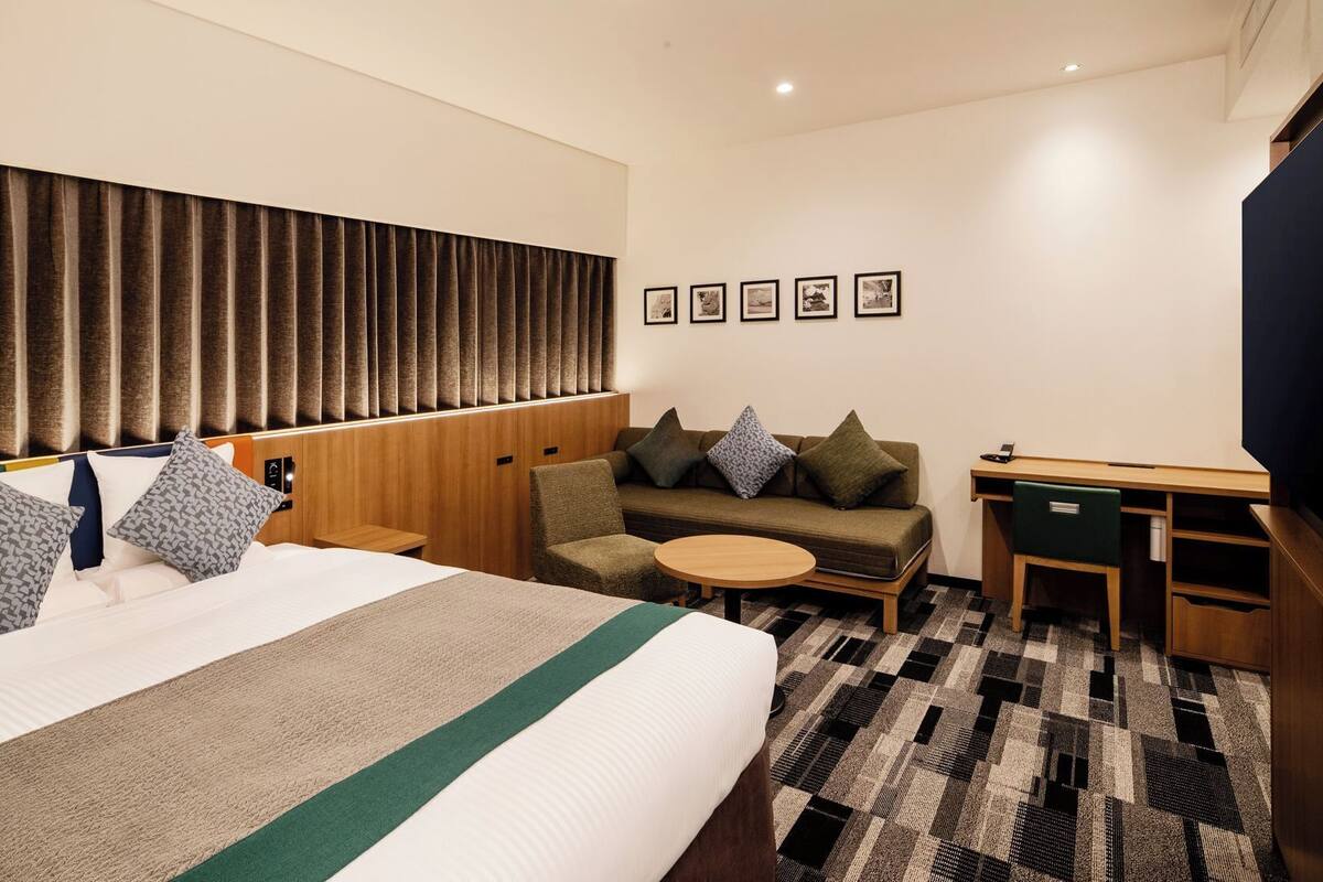 Une chambre d’hôtel avec un lit, un canapé, une petite table et un bureau.