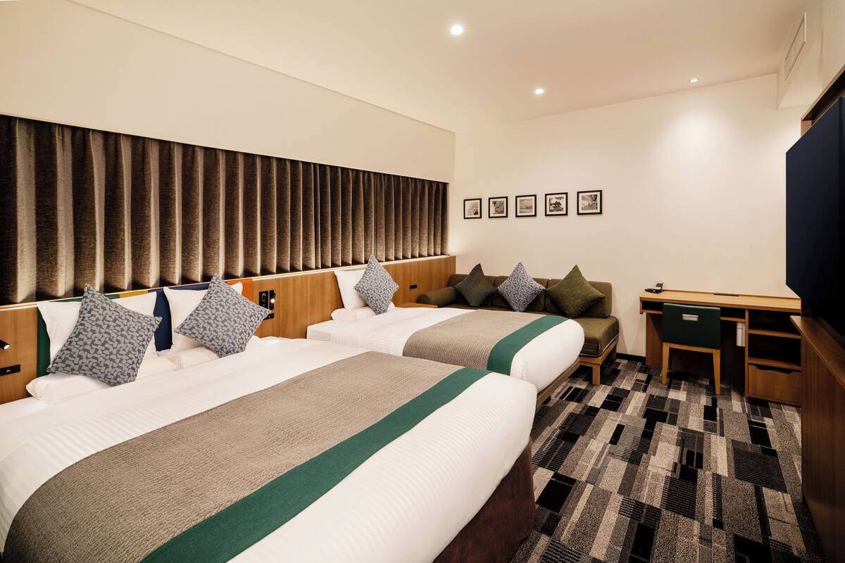 Une chambre d’hôtel avec deux lits, un bureau et une chaise.