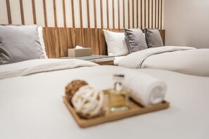 A hotel room with a wooden headboard, white bedding, and a tray with a bottle and a towel. - Muzik Hotel - Ximending Xining Branch (Taipei)