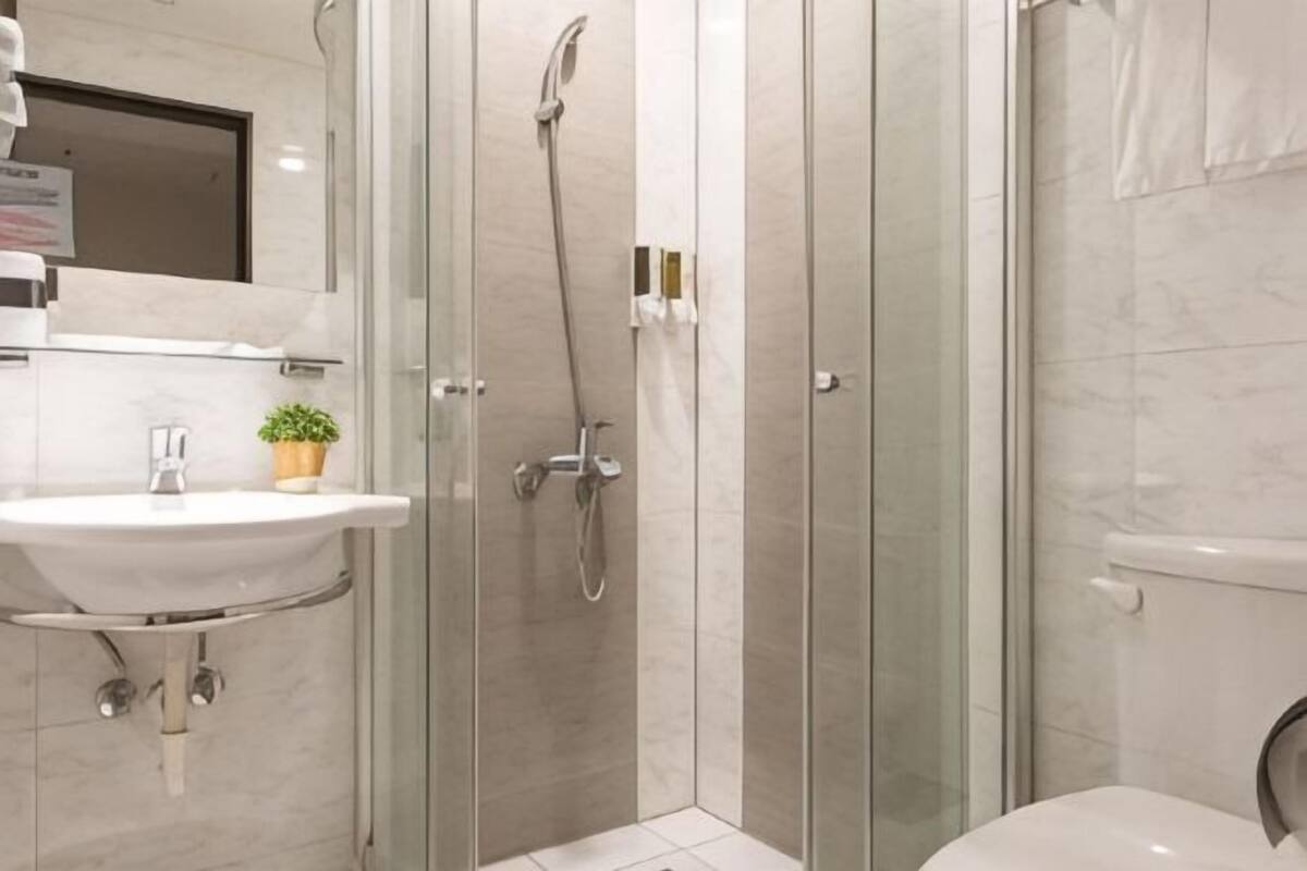 A modern bathroom with a glass-enclosed shower, a sink with a mirror, and a toilet.