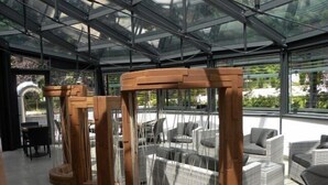 A modern outdoor seating area with wicker furniture and a glass ceiling structure. - Hotel Villa Regina (Levico Terme)