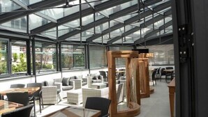 A modern indoor space with glass ceilings, wicker furniture, and wooden structures. - Hotel Villa Regina (Levico Terme)