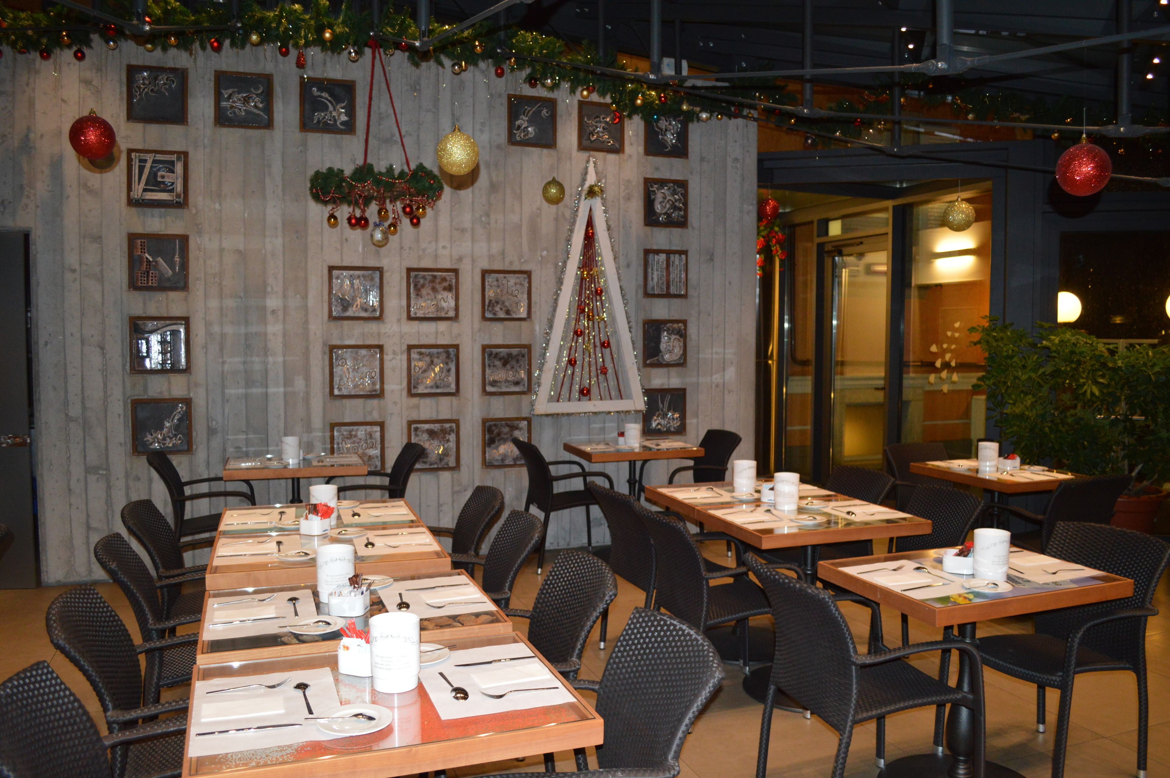 Zona pranzo con tavoli apparecchiati per più ospiti, quadri appesi alle pareti e decorazioni natalizie.