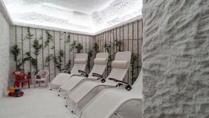 A spa room with four reclining chairs, a small table, and a few chairs. - Hotel Villa Regina (Levico Terme)
