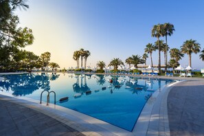 A swimming pool with lounge chairs and palm trees.