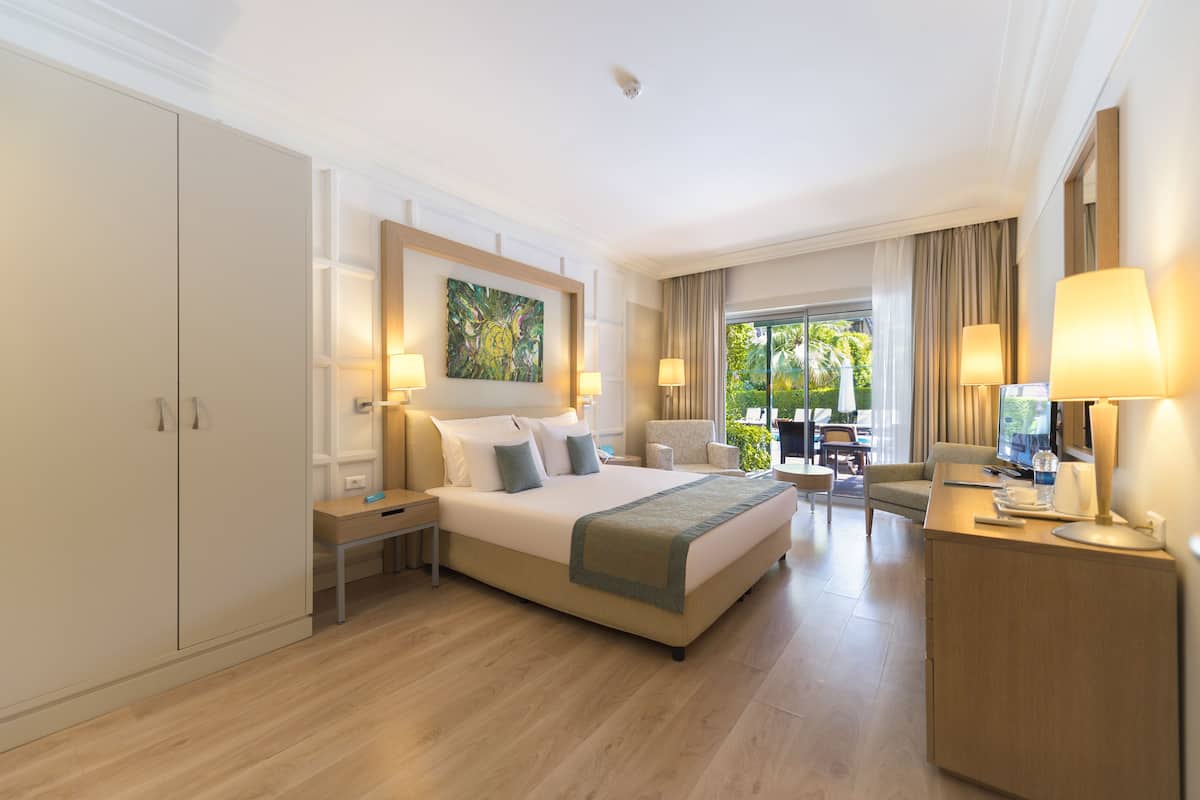 Habitación de hotel con una cama grande, mesitas de noche, un escritorio y vistas al exterior.