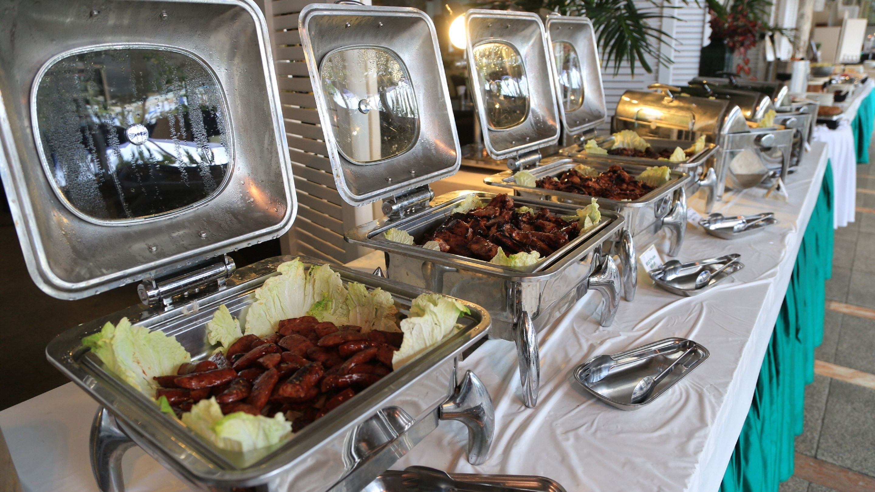 A buffet table with multiple food dispensers, including trays of meats and salads.