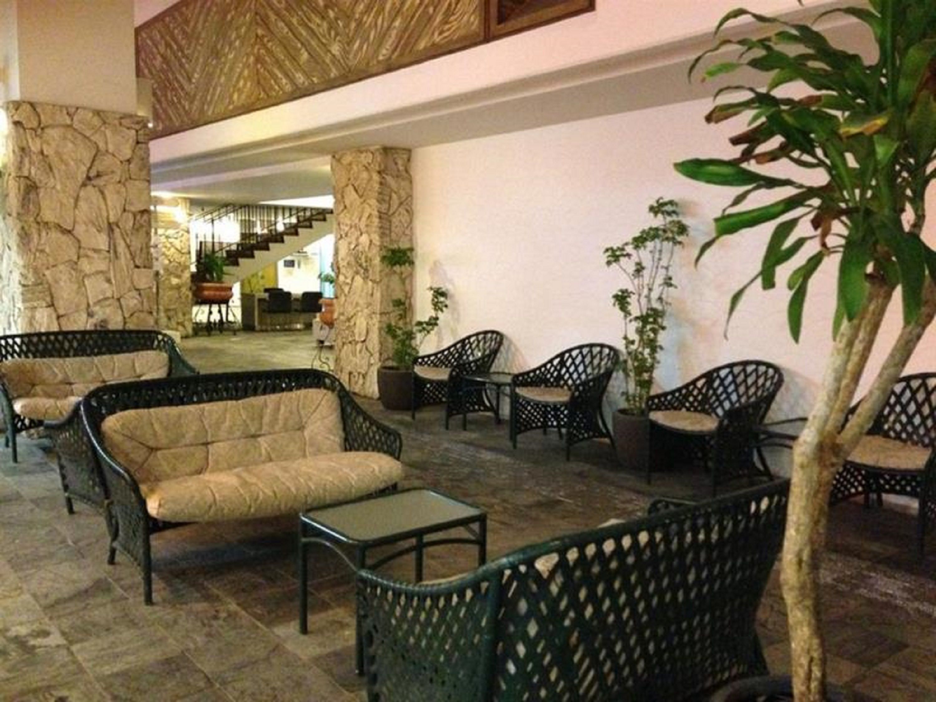 Un hall d’entrée avec des meubles en osier, des piliers en pierre et des plantes en pot.