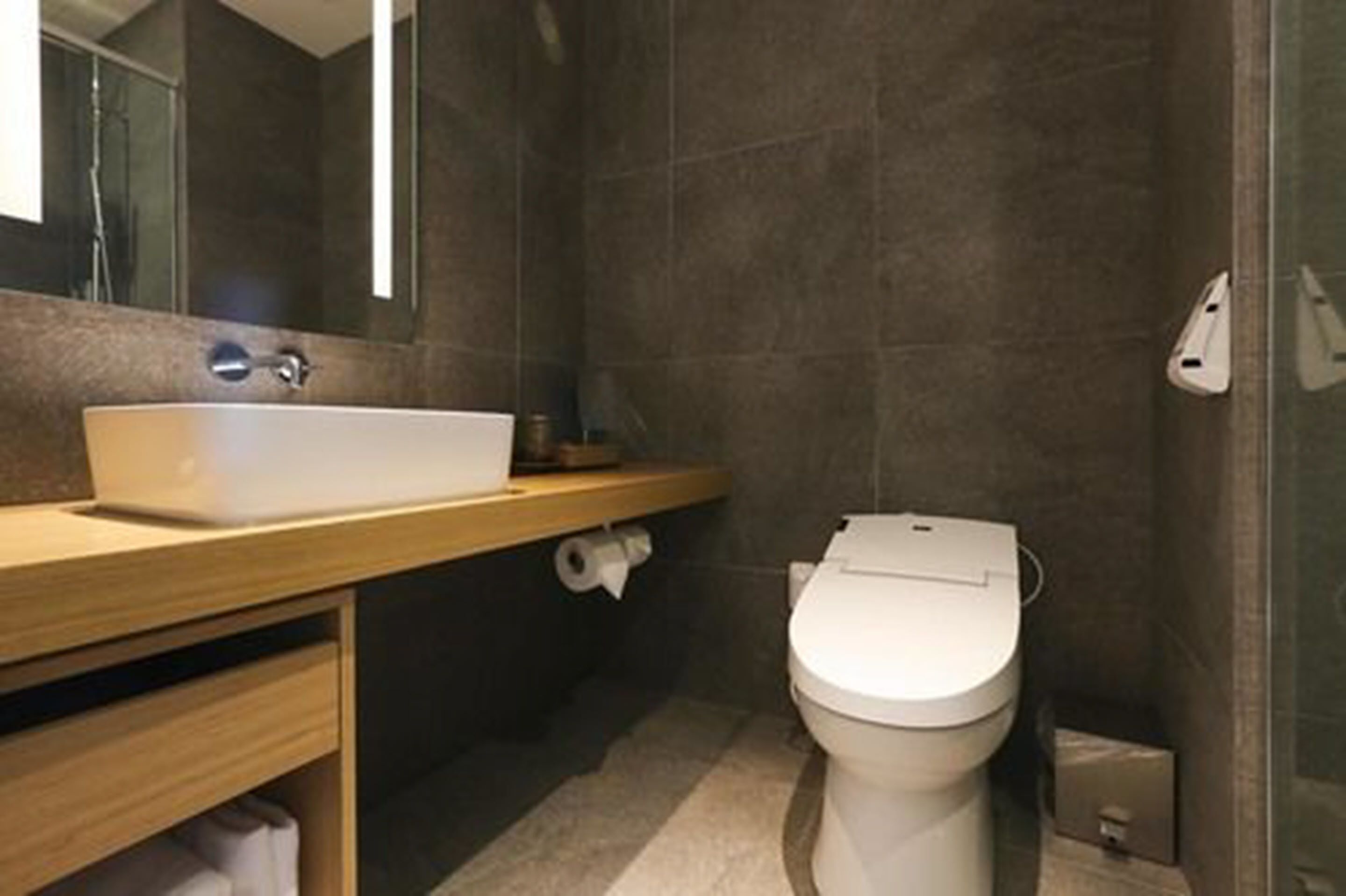 A modern bathroom with a white sink, toilet, and shower area.