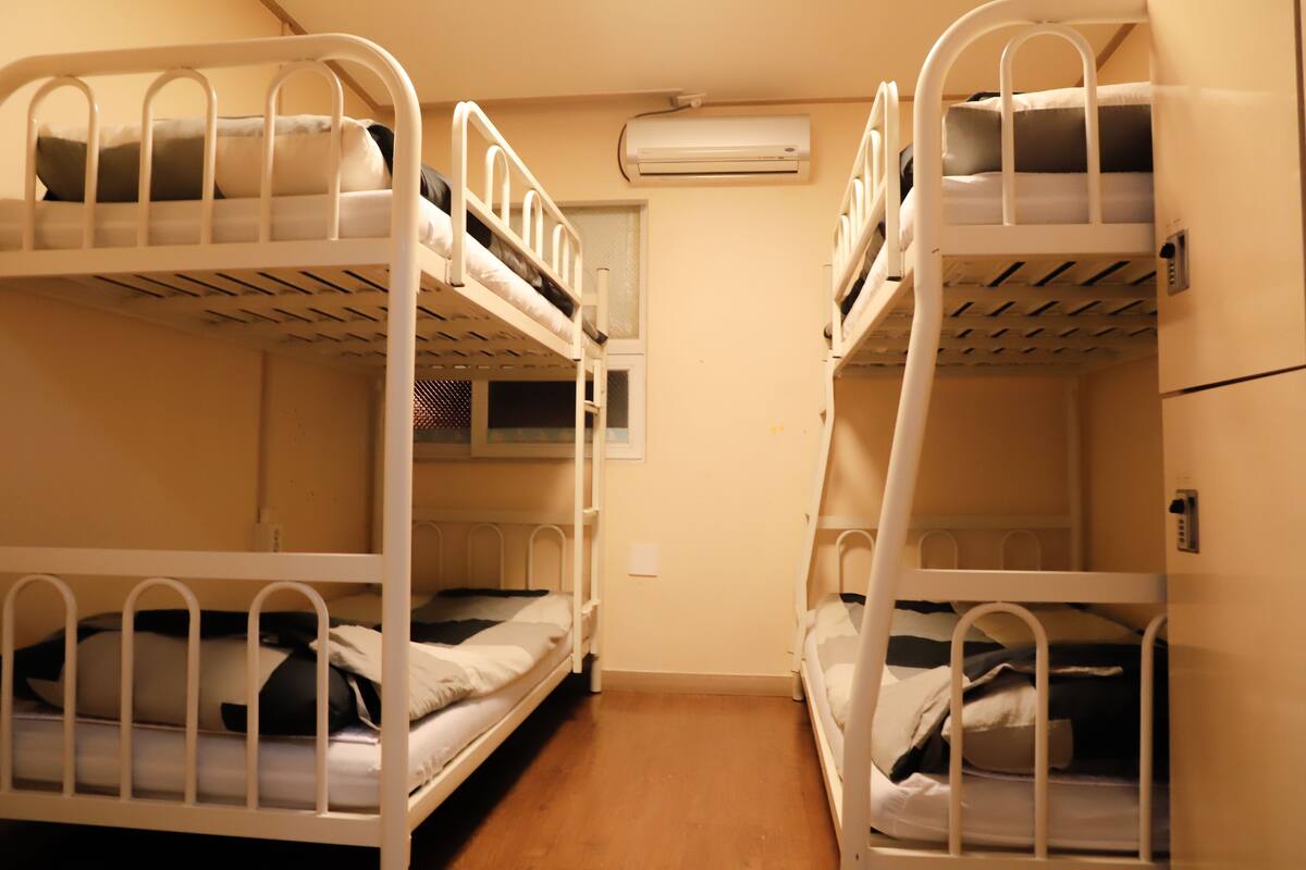 Ein Zimmer mit zwei Etagenbetten, einem Fenster und einer Klimaanlage.