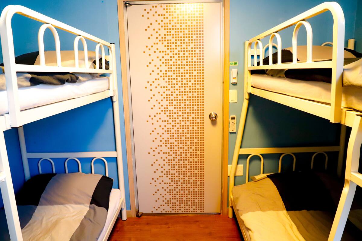 Ein Zimmer mit Etagenbetten, einer Tür mit geometrischem Muster und einer blauen Wand.
