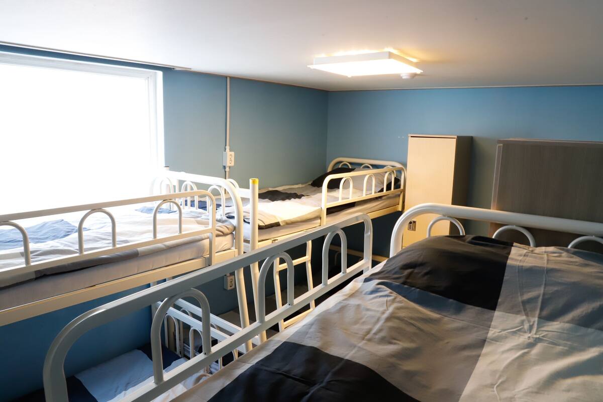 Ein Krankenzimmer mit Etagenbetten, einem Fenster und einem Nachttisch.