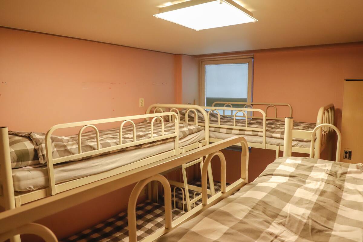 Ein Zimmer mit drei Etagenbetten, einem Fenster mit Blick und einer Deckenleuchte.
