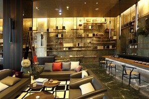 A modern interior with a sofa, chairs, a coffee table, and a bar area with shelves. - Teascape Chiayi (Chiayi City)