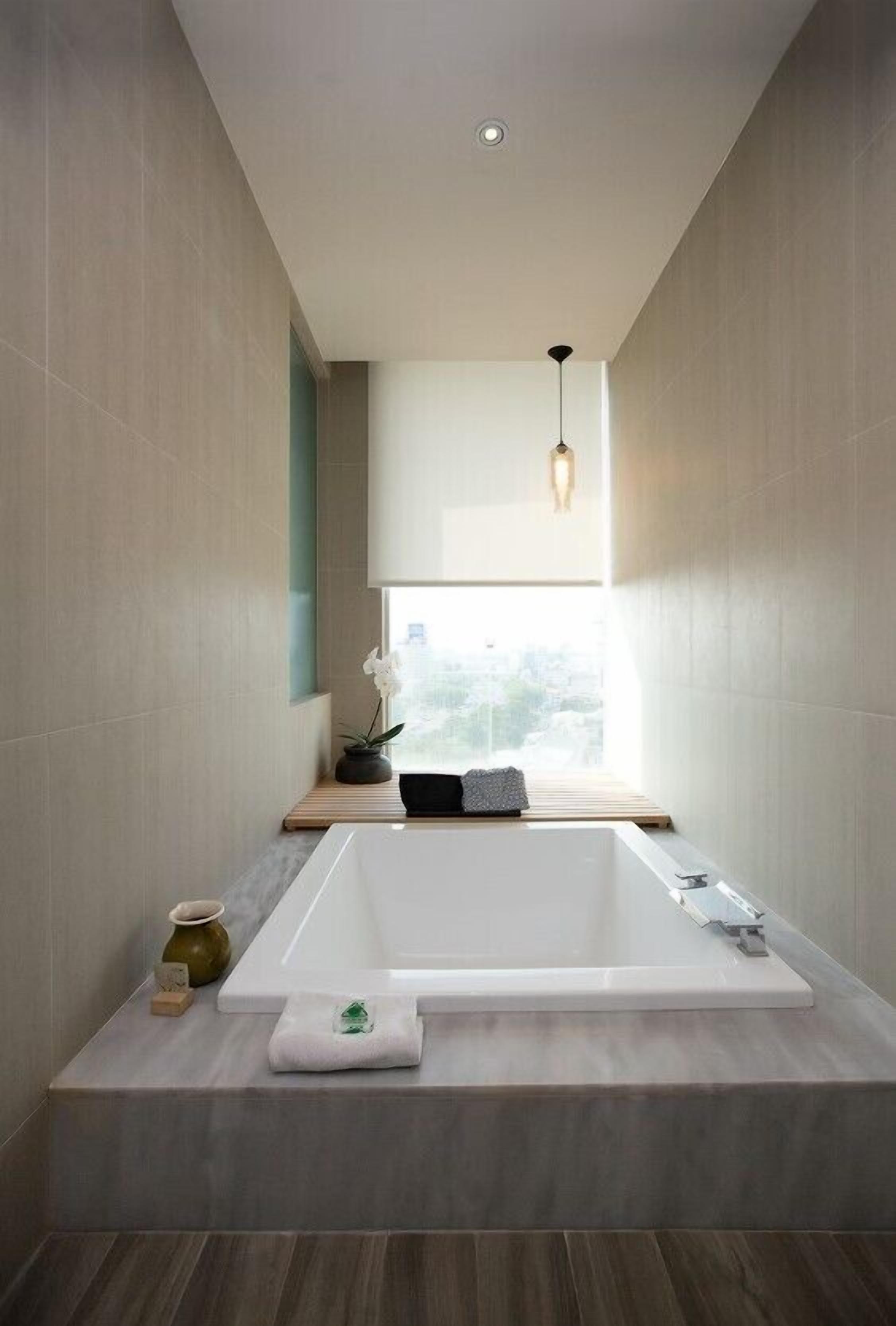 Un baño moderno con una bañera grande, una ventana con vistas y una lámpara colgante.