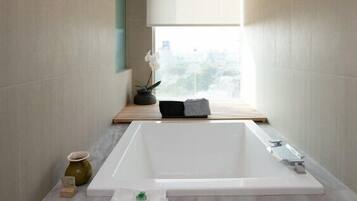 Un baño moderno con una bañera grande, una ventana con vistas y una lámpara colgante.