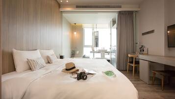 A hotel room with a large bed, a desk, and a view of the balcony.