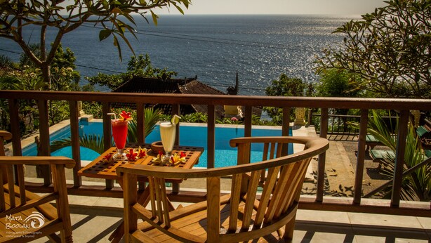 A wooden deck with a table and chairs overlooking a swimming pool and the sea. - Beten Waru (Karangasem)