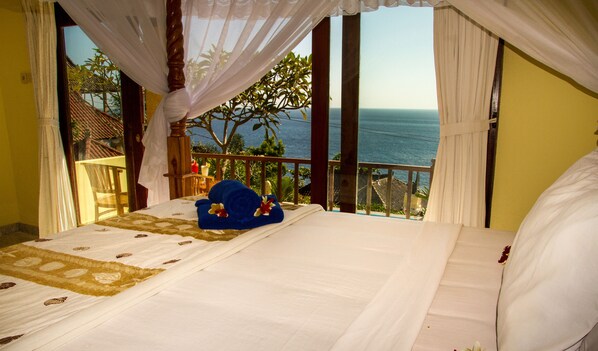 Un dormitorio con cama, vistas al océano y un balcón con plantas.