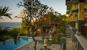 Zona junto a la piscina con sillas de descanso, una piscina pequeña y vistas al mar.