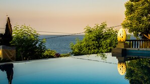 A serene pool area with a clear view of the sea, surrounded by lush greenery and a decorative structure. - Beten Waru (Karangasem)