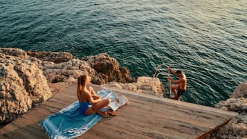 Een privéstrand, ligstoelen aan het strand, parasols, een strandbar