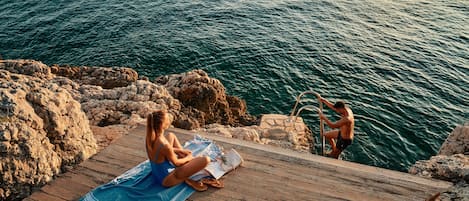 Een privéstrand, ligstoelen aan het strand, parasols, een strandbar